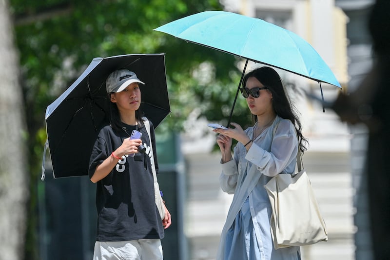 Des gens à l'abri du soleil sous des parapluies